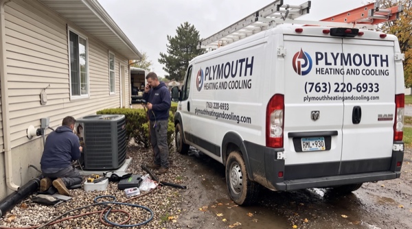 Plymouth Heating And Cooling technicians servicing AC unit at residential home